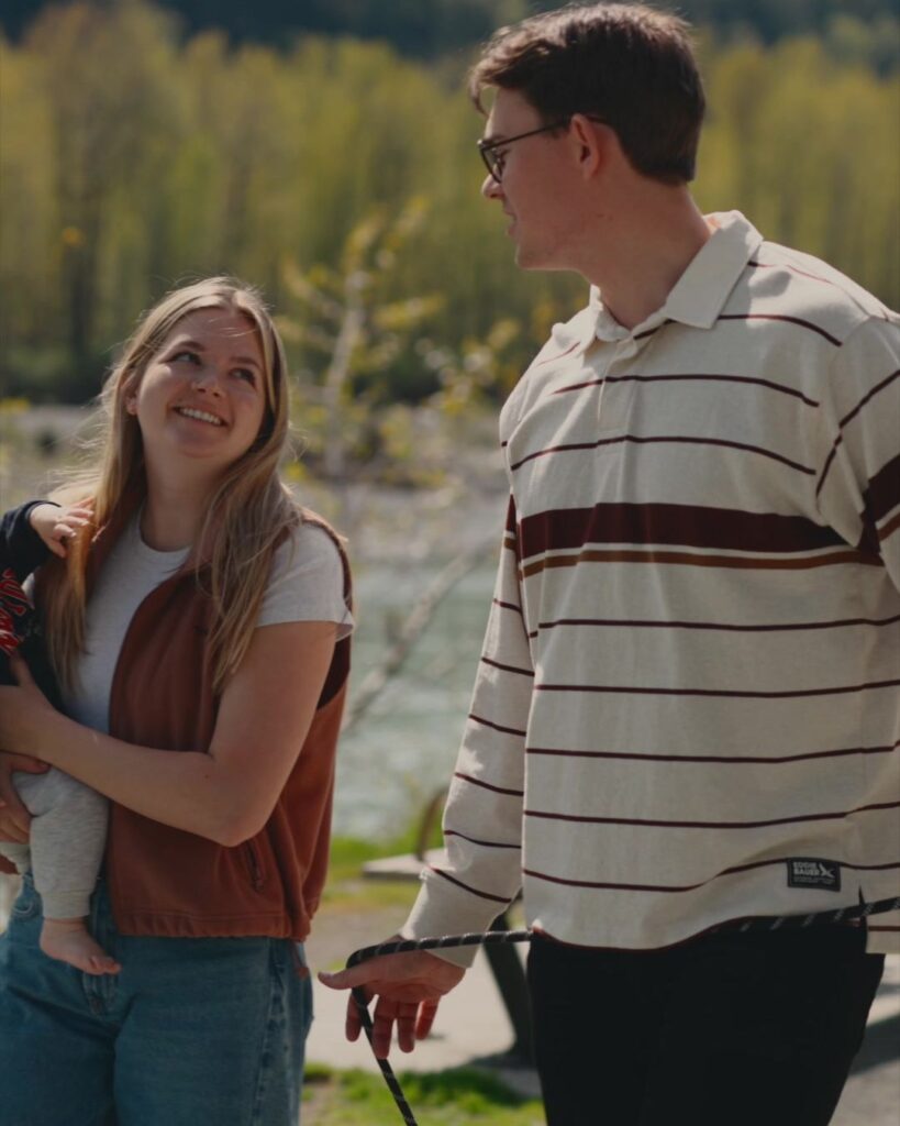 Carly Hoeppner holding their baby and laughing with Nahum by the Vedder River