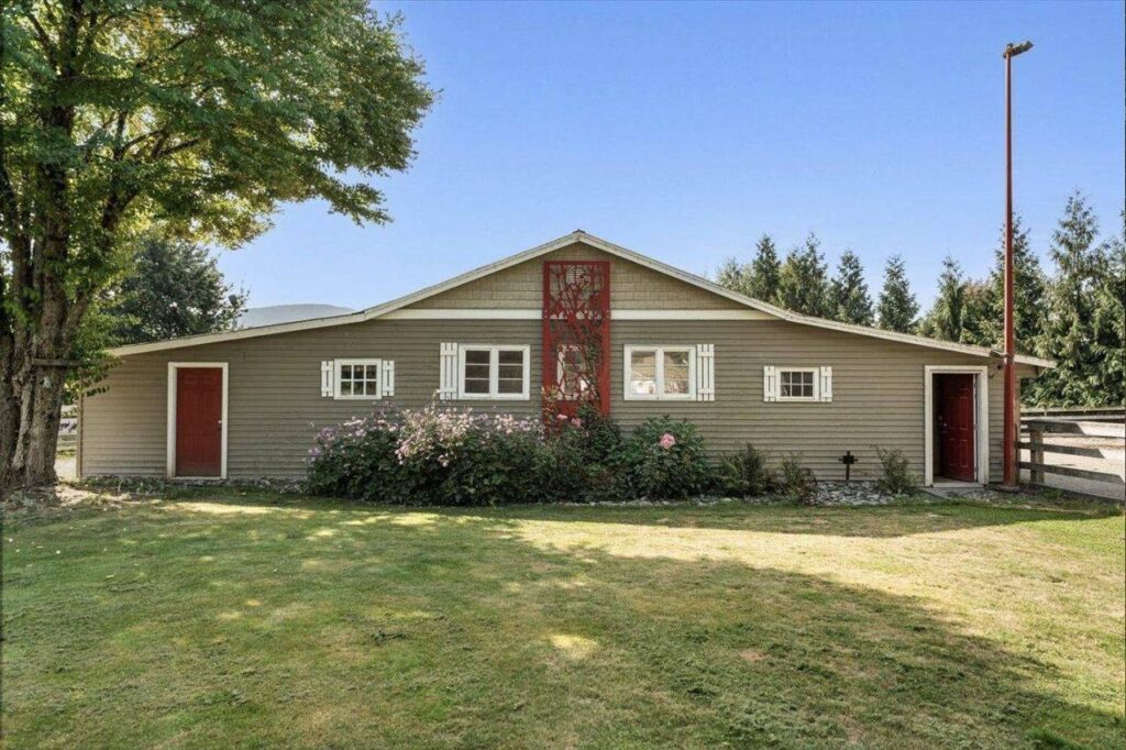 The horse barn with red doors and a garden bed at 42420 Adams Road