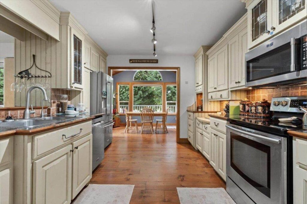 Galley kitchen with wide plank floors opening to the eating area at 42420 Adams Road