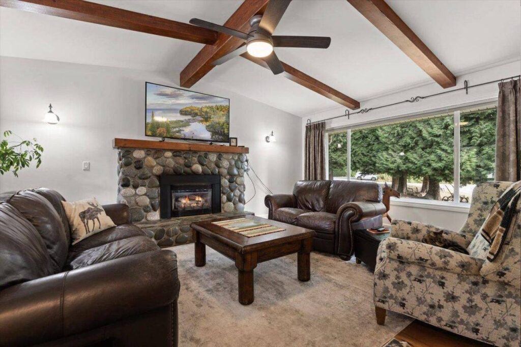Vaulted living room with beams and a river rock gas fireplace at 42420 Adams Road