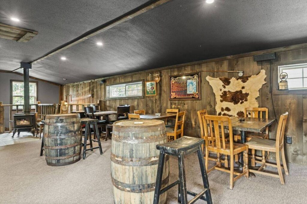 The cowboy bar with barrel tables and a wood stove at 48625 Wincott Road